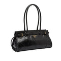 A black Prada leather handbag displayed on a dark table with its white dust bag, shopping bag, and strap laid out in front. The Prada logo is visible on the bag and shopping bag.
