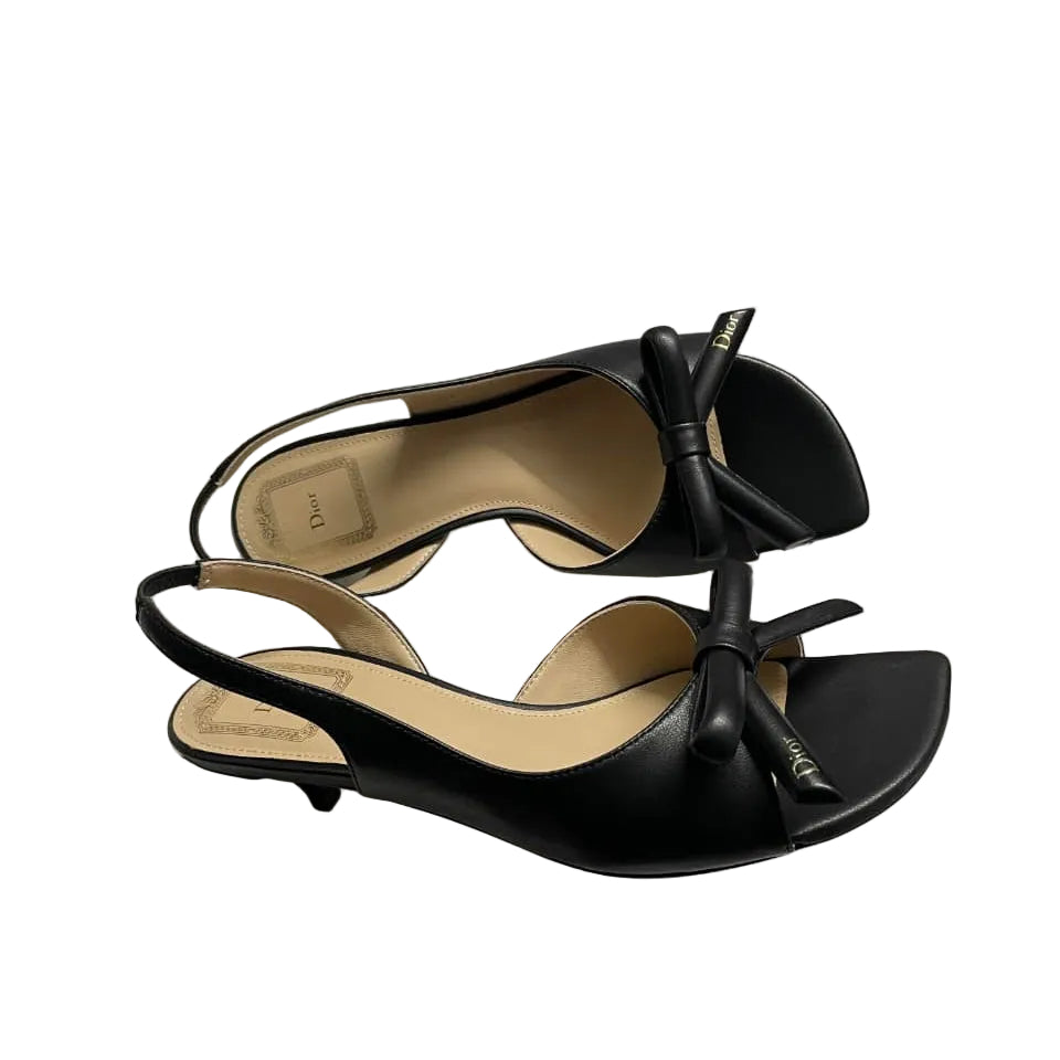 A pair of black leather Christian Dior slingback mule sandals with bow details, displayed on top of their white Dior shoebox.